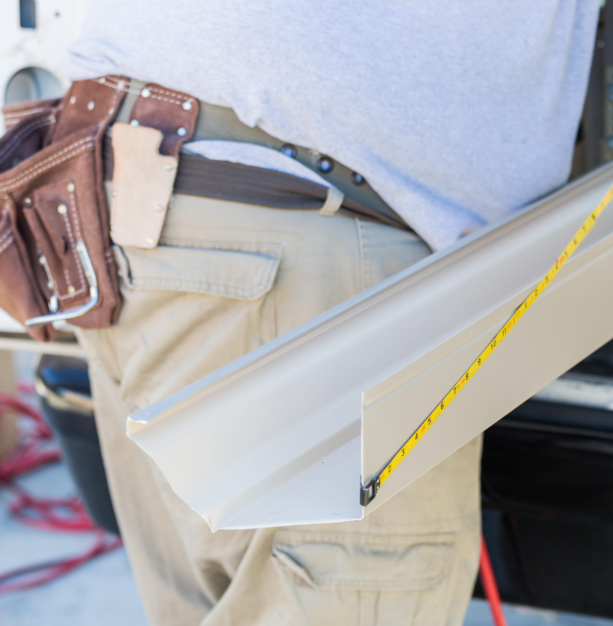 Worker Measuring An Aluminum Rain Gutter Feeding Through Seamless Shaping Machine.